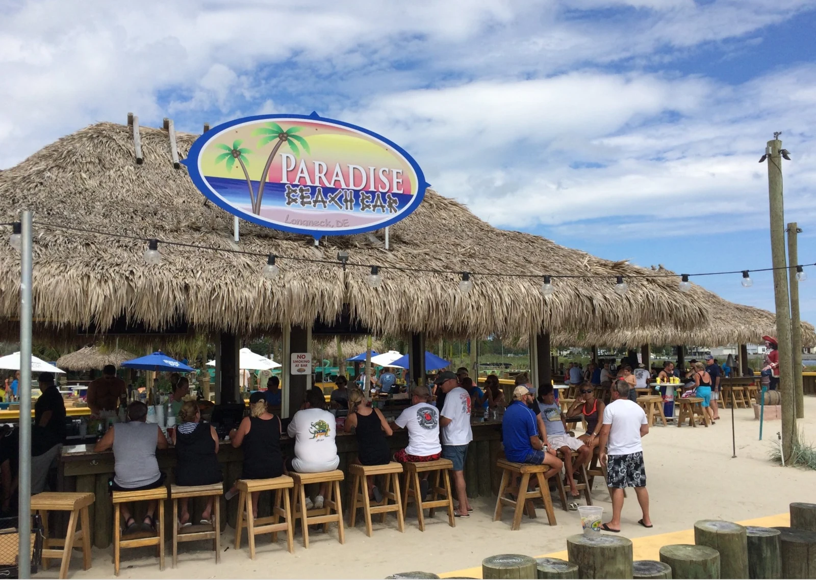 Guests gathered around a thatched tiki bar at Paradise Grill